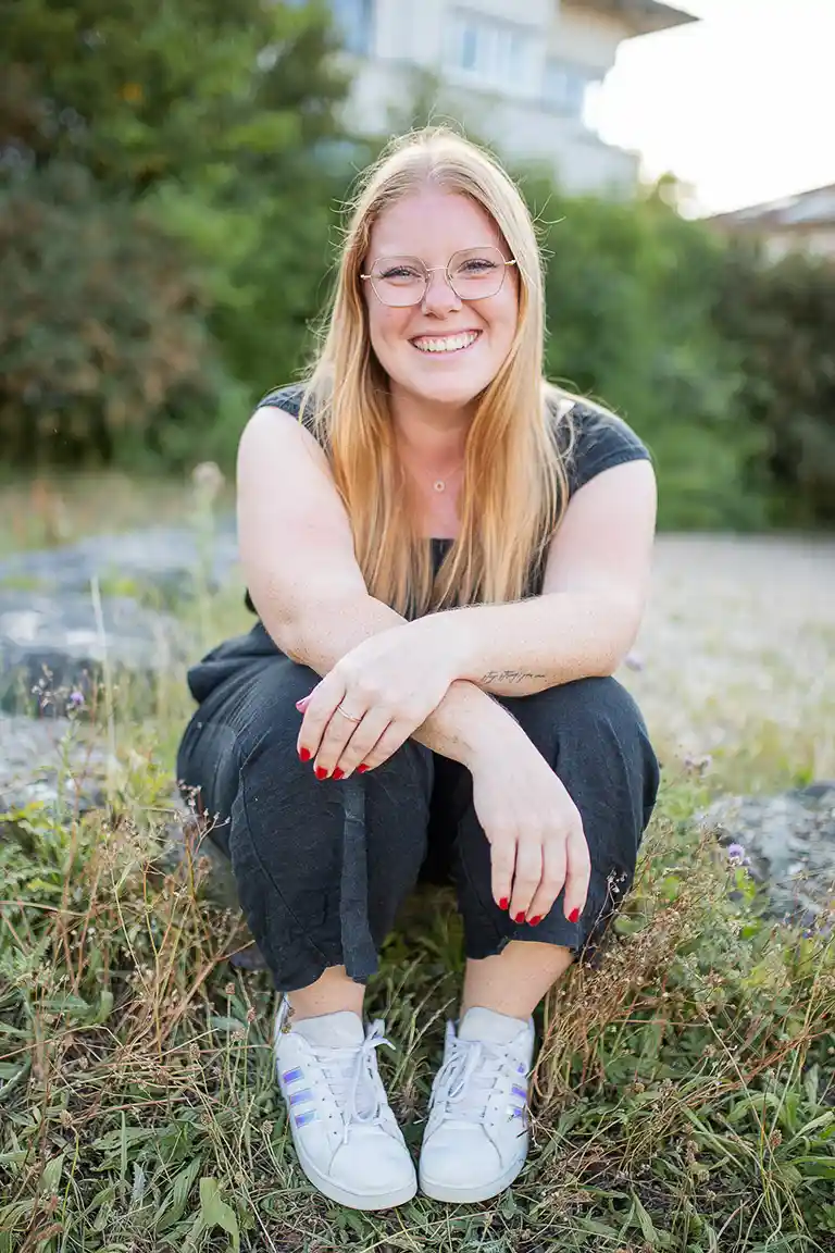 Hochzeitsfotografin Susanne Kroll aus Ludwigsburg sitzt lächelnd in einer Sommerwiese